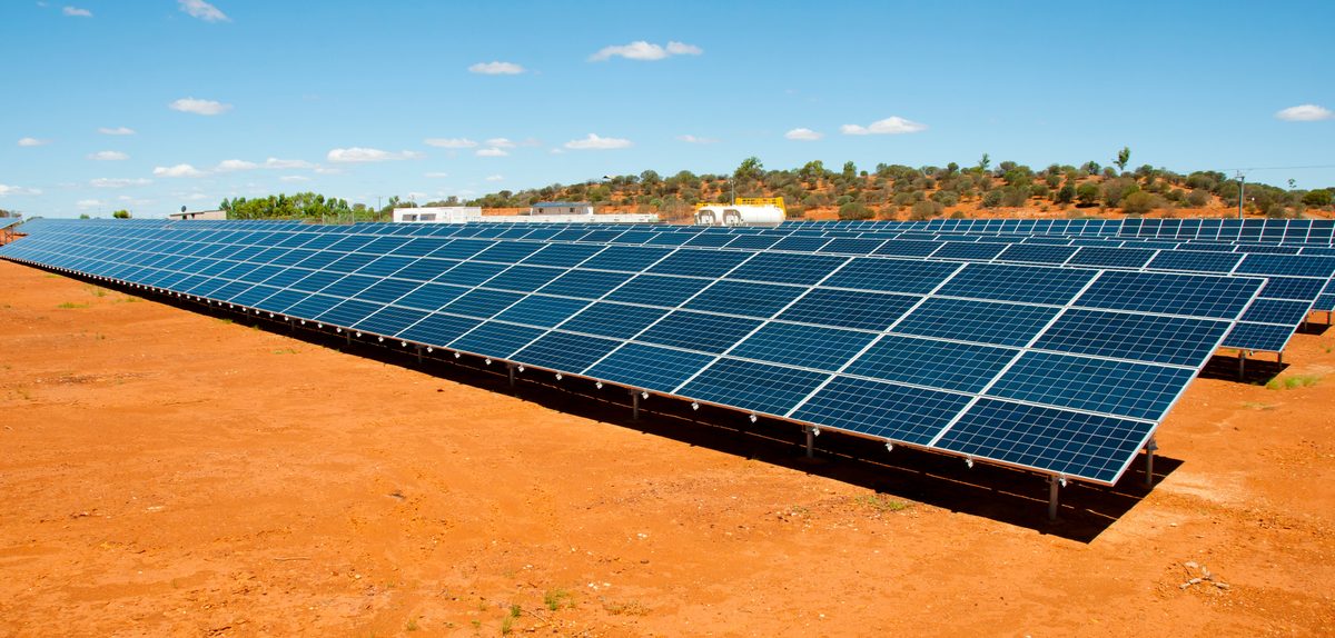 Rows of solar panels on red earth under an open sky